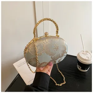 Dettaglio borsa da sera in raso celeste con ricamo floreale dorato e manico in metallo