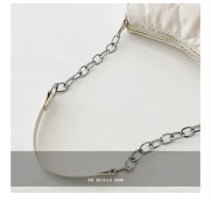 Détail de la chaîne en métal argenté poli sur un sac à bandoulière matelassé crème