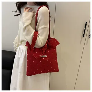 Détail du sac cabas rouge à fleurs avec volants et logo de la marque cousu
