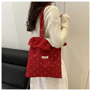 Gros plan du sac fourre-tout floral rouge avec volants et étiquette de marque tissée