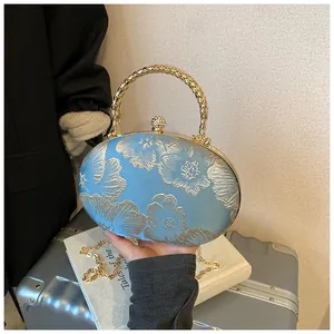 Dettaglio macro della borsa da sera blu con ricami floreali dorati e chiusura in strass