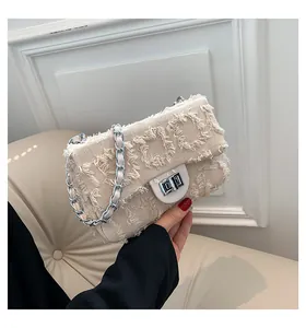 Détail du tissu en tweed beige avec textures de franges et fermoir rotatif en métal argenté