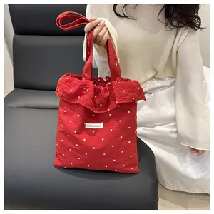 Détail du sac cabas rouge à fleurs avec bords à volants et étiquette Agogo Original