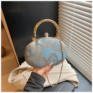 Dettaglio della borsa da sera blu con ricami floreali dorati e chiusura a diamante