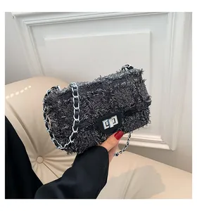 Détail de la texture en tweed gris et de la chaîne argentée sur le sac à bandoulière