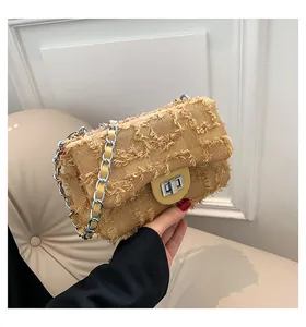 Gros plan d'un sac à chaîne kaki avec texture en toile effilochée et fermoir rotatif argenté