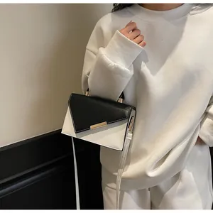 Modella che indossa una borsa a tracolla bicolore bianco e nero con fibbia dorata
