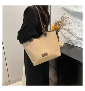 Detail of knotted shoulder strap and contrast brown trim on beige leather tote bag