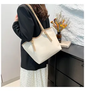 Side view of large cream tote bag with khaki straps worn with a black blazer