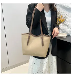 Detail of beige leather tote bag with brown straps and adjustable gold buckles for women
