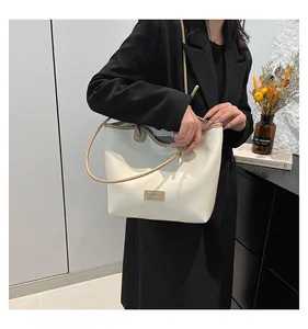 Detail of minimalist cream tote bag showing fashion tag, brown trim and slim straps