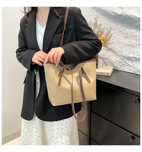 Beige tote bag with brown straps worn by a model in a professional office setting