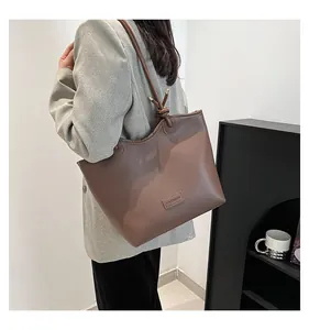 Detail of a brown leather tote bag with FASHION patch and knotted shoulder strap