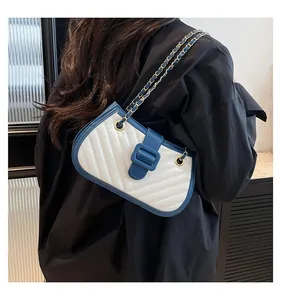 Detail of blue and white quilted crossbody bag featuring elegant gold chain strap