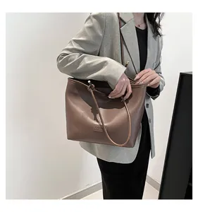 Close-up of a large dark brown tote bag in faux leather with a minimalist fashion label