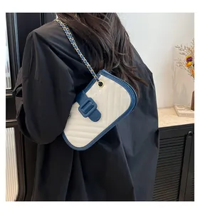 Detail of V-quilted faux leather crossbody bag with navy trim and gold chain strap