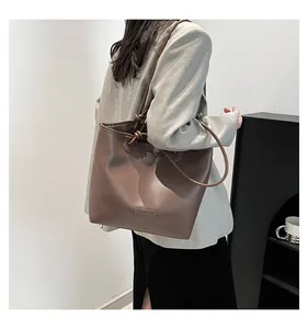 Close-up of matte dark brown large tote bag with knotted strap and Fashion logo patch
