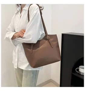 Detail of a large brown leather tote bag with adjustable straps and gold hardware