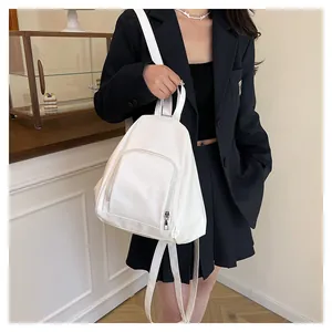 Détail d'un sac à dos blanc en nylon avec zips métalliques sur un costume noir chic