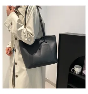 Détail du sac cabas en cuir noir minimaliste avec une poche avant à bouton rond