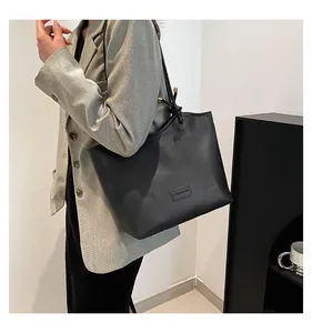 Detail of a black large-capacity tote bag with FASHION logo worn by a model