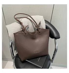 Detail of dark brown tote bag featuring knotted shoulder straps and silver metal tips