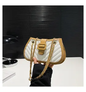 Detail showing V-shaped quilted texture and large square buckle on a stylish flap bag