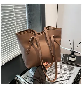 Close-up of brown synthetic leather tote bag with subtle embossed letters and shoulder strap