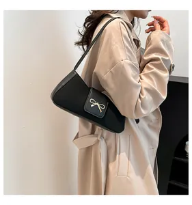 Detail einer schwarzen Leder-Baguette-Tasche mit goldener Schleifenschnalle am Modell