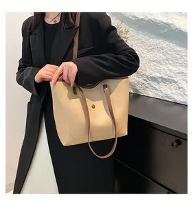 Grand sac fourre-tout beige avec lanières marron porté à l'épaule par un mannequin