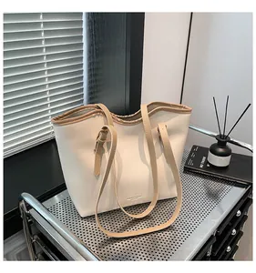 Close-up of cream tote bag with brown straps and engraved fashion leather logo on cart