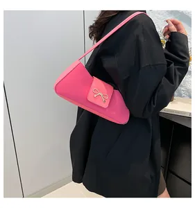 Detailansicht der pinkfarbenen Schultertasche aus Leder mit goldenem Schleifenanhänger