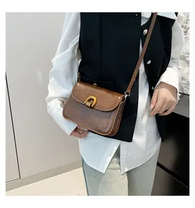 Detail der vintage-braunen Ledertasche mit goldener Hufeisenschnalle an der Schulter