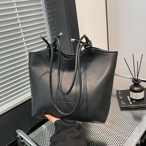 Minimalist large black tote bag in matte synthetic leather with fashion tag detail