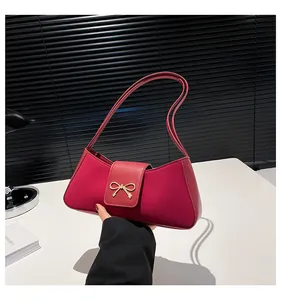 Detail einer magentafarbenen Ledertasche mit einer goldenen Schleifenschnalle aus Metall