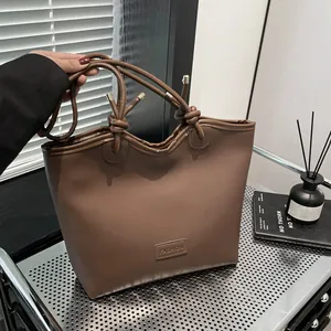 Brown faux leather tote bag with stylish knot handles and a casual minimalist silhouette