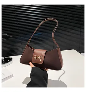 Detailansicht der dunkelbraunen Baguette-Tasche mit dekorativer goldener Schleifenschnalle