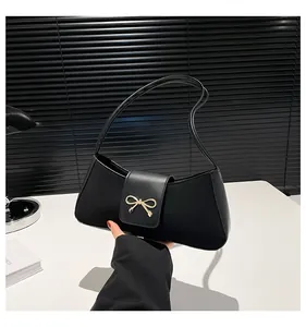 Detailansicht der goldenen Schleife an der schwarzen Leder-Baguette-Tasche für Damen