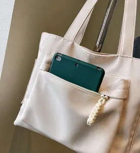 Dettaglio della tasca frontale con zip su questa borsa tote in tela beige per riporre