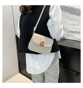 Nahaufnahme der cremefarbenen Tasche mit goldener U-Schnalle und verstellbarem Schultergurt