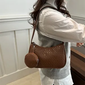 Braune geflochtene Ledertasche mit abnehmbarem Münzfach an einem weiblichen Model