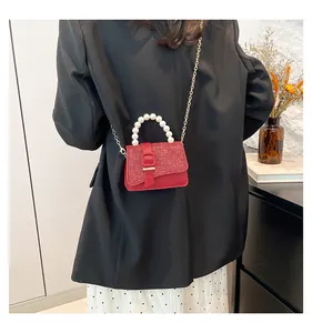 Detailed view of red mini crossbody bag featuring glitter flap and pearl handle
