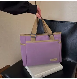 Detailansicht lila Canvas-Tasche mit khakifarbenen Trägern und Lederetikett-Applikation