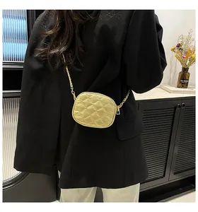 Detail of light yellow quilted mini bag with gold chain strap worn over the shoulder