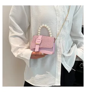 Detail of pink crossbody bag with rhinestone flap, pearl handle and gold chain strap