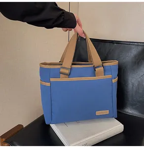 Detail der blauen Canvas-Tragetasche mit braunen Trägern und praktischer Vordertasche