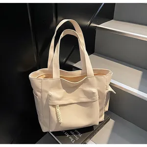 Detail of a beige canvas tote bag with large front pocket and woven rope zipper trim