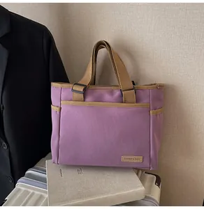 Detailansicht einer lila Segeltuch-Tasche mit braunen Trägern und gewebtem Mode-Etikett