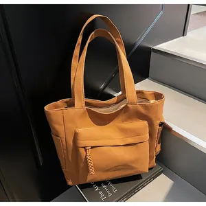 Detailed macro view of caramel canvas tote bag showing front pocket and durable texture