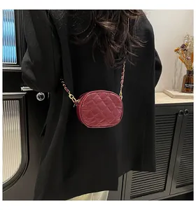 Close-up of quilted burgundy leather mini crossbody bag with gold chain strap on shoulder